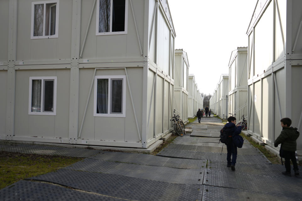 Children returning from school walk between container apartments at the Ukraine village, which has been constructed for Ukrainian families fleeing the war, in Linkeroever, Belgium, Friday, March 17, 2023. Despite the warm welcome for millions of Ukraine refugees on European Union soil since the Russian invasion, EU officials said Tuesday, June 6, 2023 that there are some fears of wavering support caused by a bad economy hitting poor families especially and the creeping influence of Russian propaganda. (AP Photo/Virginia Mayo)