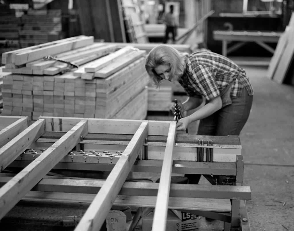 1960s 1970s WOMAN JOINING BOARDS WITH NAIL GUN IN PREFAB HOME FACTORY