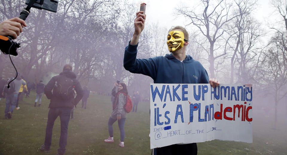 A protester with a flare poses holding a sign calling for people to 