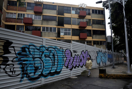 Maria Guadalupe Padilla walks past near the site where her building was damaged by the devastating in the Tlalpan neighbourhood, that took place in Mexico City last year Mexico, September 12, 2018. Picture taken September 12, 2018. REUTERS/Henry Romero