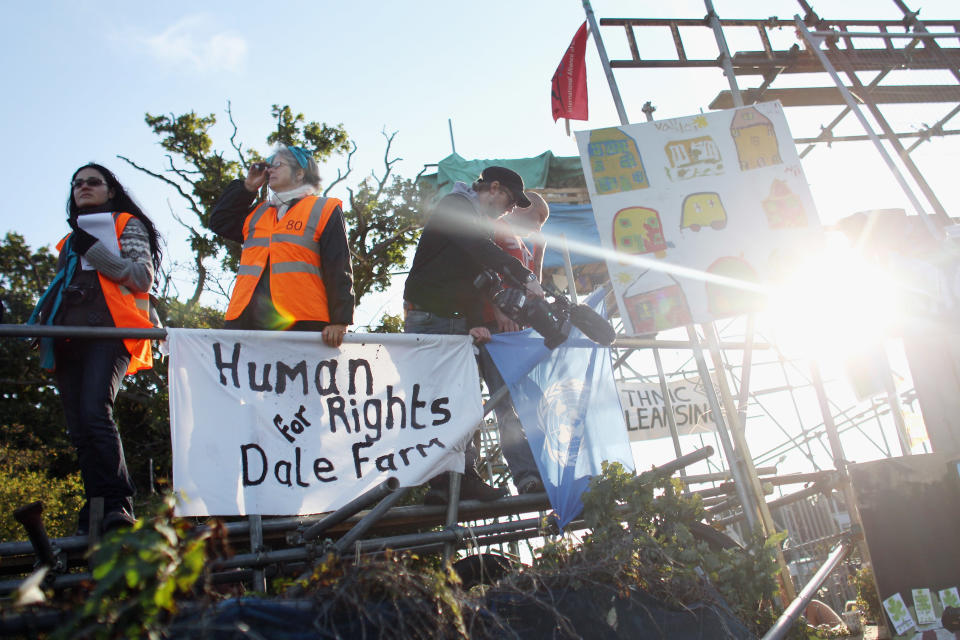 BASILDON, ENGLAND - SEPTEMBER 19: Activists and legal observers stand on barricades next to the main gate at Dale Farm travellers camp on September 19, 2011 in Basildon, England. Eviction of 80 traveller famillies is to begin after a 10 year legal battle to clear the site of illegal dwellings. Residents and activists have built barricades around the site to resist bailiffs.