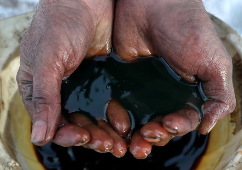 FILE PHOTO: An employee demonstrates a sample of crude oil in the Irkutsk Oil Company-owned Yarakta Oil Field in Irkutsk Region