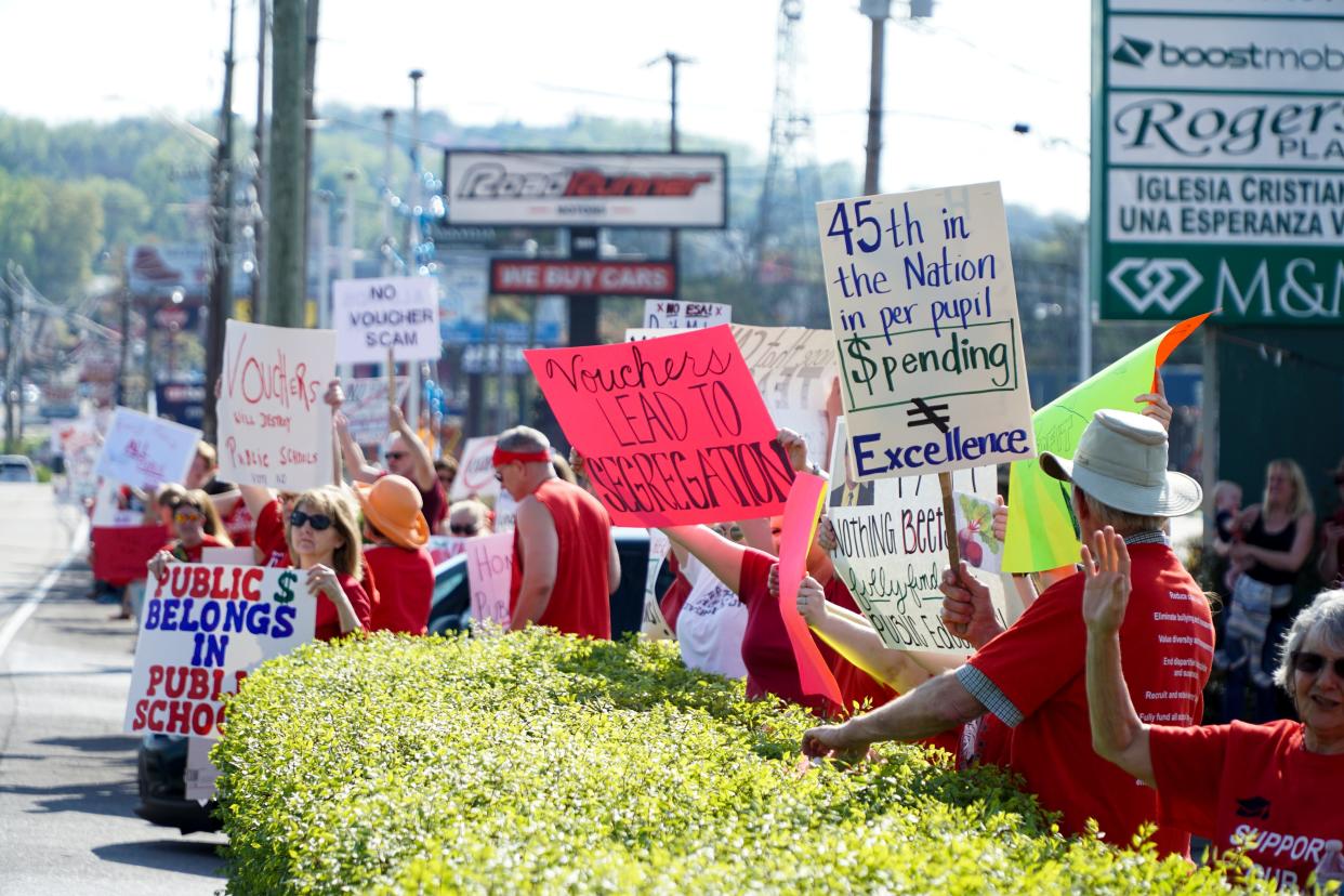 Demonstrators hold signs along Kingston Pike in front of Rothchild Catering in opposition to a bill that would create  education savings accounts for Tennessee students.