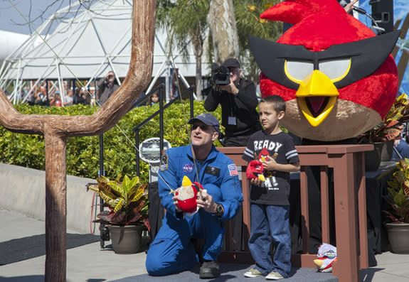 At NASA’s Kennedy Space Center Visitor Complex in Florida, NASA astronaut Don Pettit uses a giant slingshot to launch a plush Angry Bird character during the grand opening of the new Angry Birds Space Encounter. Standing behind Pettit is Red Bi