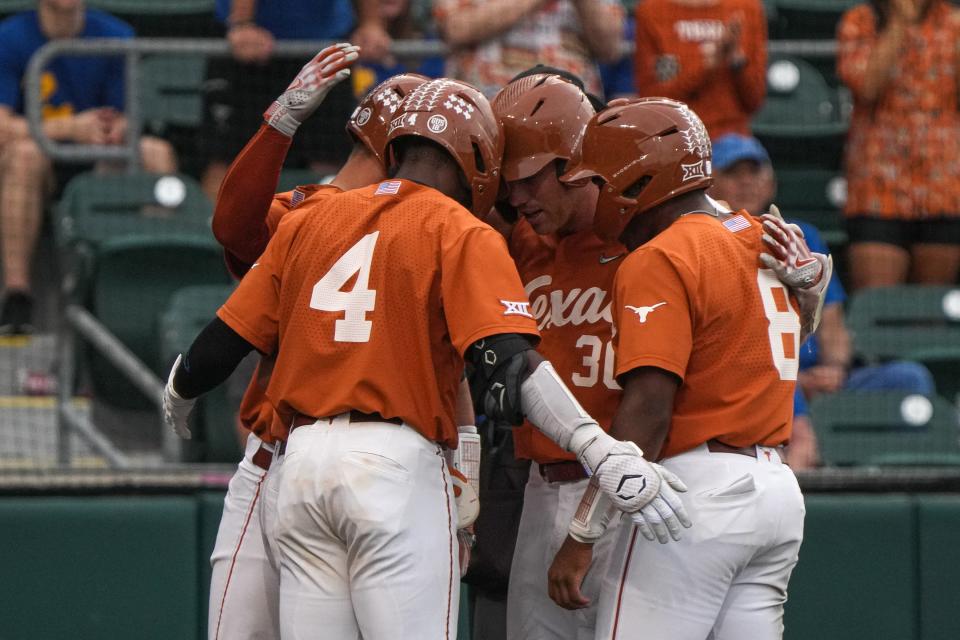 Texas players gather around Eric Kennedy to celebrate his grand slam during the Longhorns' 24-3 rout of San Jose State on Friday.