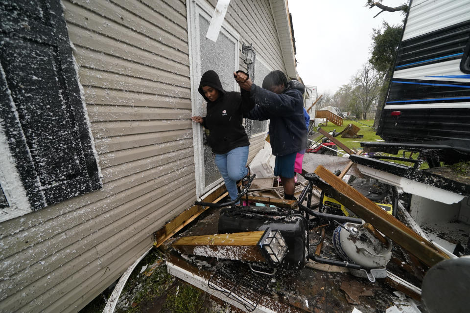 Personas recorren los escombros tras el paso de un tornado en Killona, Luisiana, a unos 48 kilómetros (30 millas) al oeste de Nueva Orleans, en el distrito St. James, el miércoles 14 de diciembre de 2022. (AP Foto/Gerald Herbert)