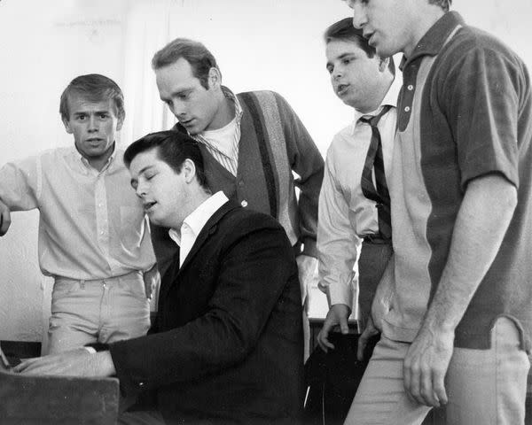 <p>Michael Ochs Archives/Getty</p> Brian Wilson and the Beach Boys gather around the piano, 1964