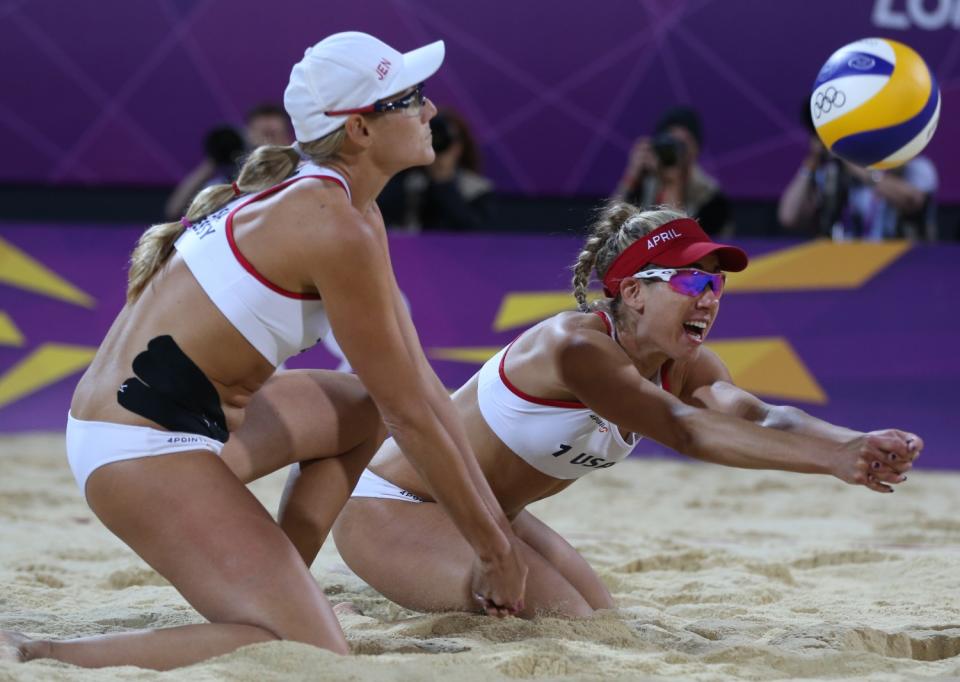 Jennifer Kessy and April Ross on their knees in the sand as they try to reach the volleyball.