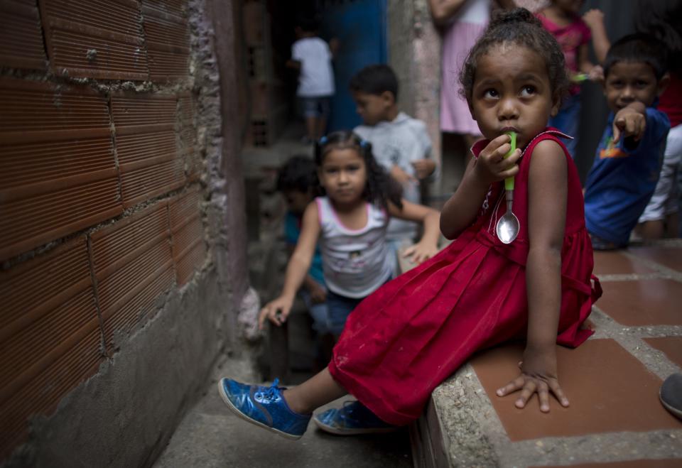 En esta imagen, tomada el 26 de agosto de 2018, una niña sostiene su cuchara mientras espera para recibir la comida en un centro infantil en el vecindario de La Vega, en Caracas, Venezuela. El activista opositor Roberto Patiño dijo que abandonó sus ambiciones políticas para centrarse en alimentar a 1.800 niños cinco días a la semana en 21 barrios pobres capitalinos. (AP Foto/Ariana Cubillos)