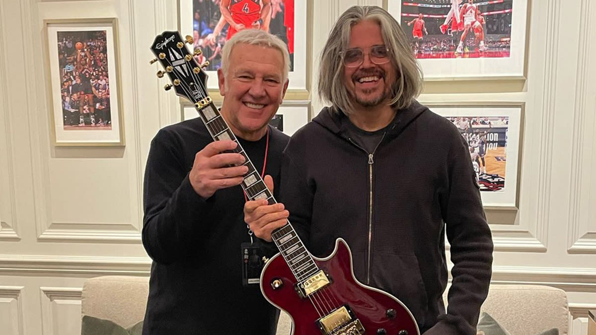  Alex Lifeson and Adam Jones holding an Epiphone Alex Lifeson signature Les Paul. 