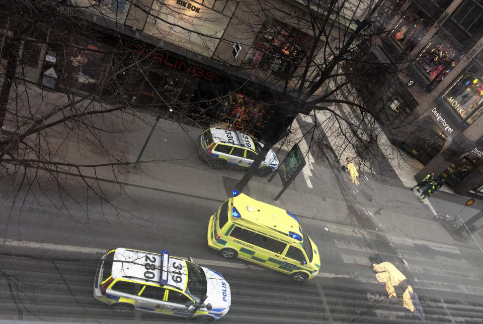 Members of the emergency services attend the scene after a truck crashed into a department store injuring several people in central Stockholm, Sweden, Friday April 7, 2017. Swedish Prime Minister Stefan Lofven says everything indicates a truck that has crashed into a major department store in downtown Stockholm is "a terror attack." It cannot be confirmed what is under the sheets at right. (TT News Agency via AP)