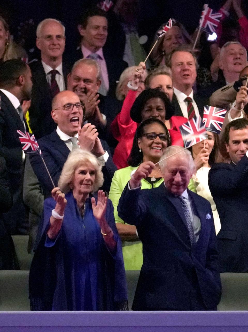 Queen Camilla and King Charles wave flags at the concert (POOL/AFP via Getty Images)