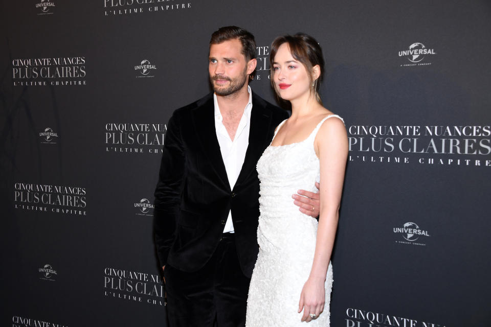 Jamie Dornan and Dakota Johnson pose together at a "Cinquante Nuances Plus Claires" premiere, with Jamie in a black suit and Dakota in a dress