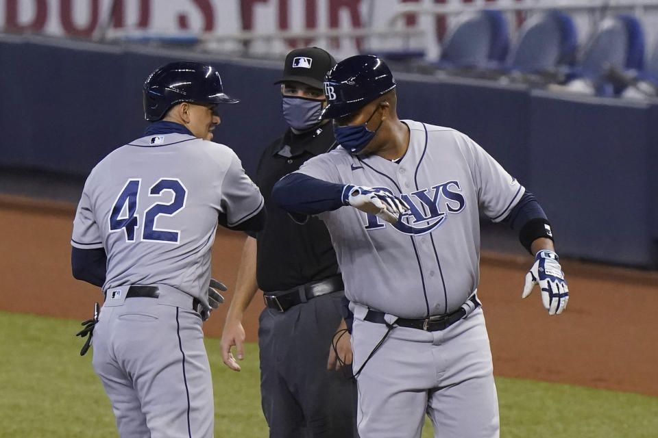 Tampa Bay Rays' Willy Adames, left, is congratulated by first base coach Ozzie Timmons after getting a base hit during the first inning of a baseball game against the Miami Marlins, Sunday, Aug. 30, 2020, in Miami. (AP Photo/Wilfredo Lee)