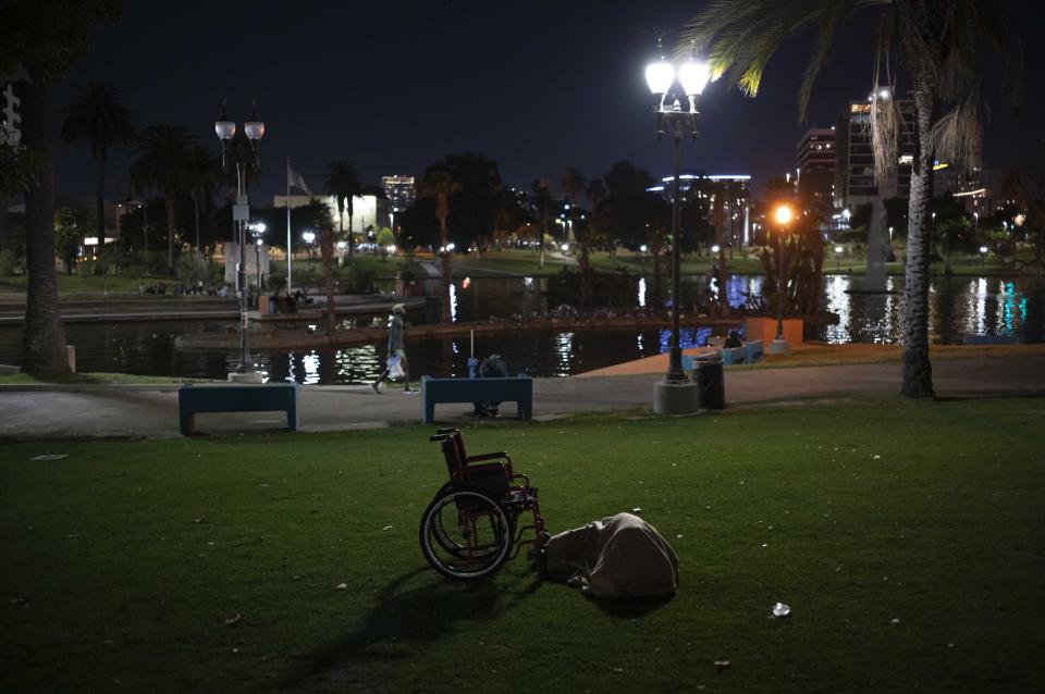 A homeless person with a wheelchair sleeps in MacArthur Park in Los Angeles, Friday, Oct. 13, 2023. (AP Photo/Jae C. Hong)