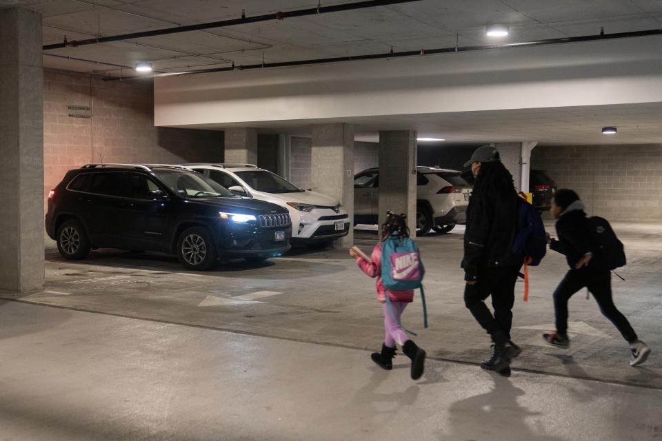 Johnae Strong, her 10-year-old son Akeim Smith and 6-year-old daughter Jari Akim rush to their car as they leave for school and work Friday, Feb. 10, 2023, in Chicago. Strong, a single mother of two, lost her partner and father to her daughter Jari, Malik Alim, when he drowned in in a boating accident while saving Jari and his son Ori in 2021. She said she usually spends over 40 hours per week doing clerical work for a small media company and as an independent filmmaker. "Childcare is generally the biggest challenge," she said. (AP Photo/Erin Hooley)