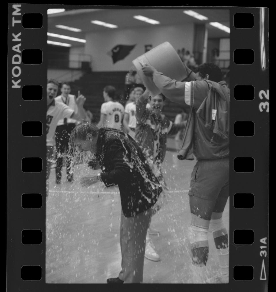 The Ball State University men's volleyball team celebrates with coach Don Shondell after their win at the 1988 MIVA playoff game in Irving Gymnasium.