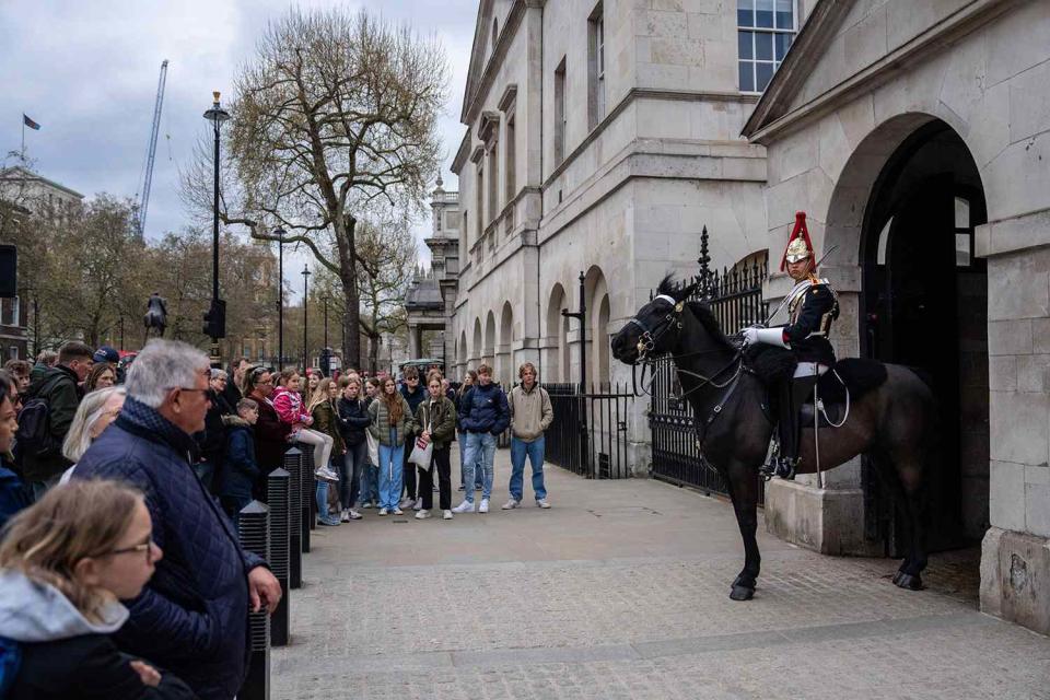 <p>Carl Court/Getty</p> Tourists gather around a mounted cavalry trooper of The King