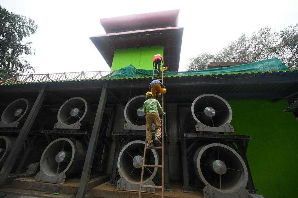 Workers climb a ladder at the 25-metre (82-foot) high smog tower, built to purify the air during peak pollution season, in New Delhi (AFP via Getty Images)