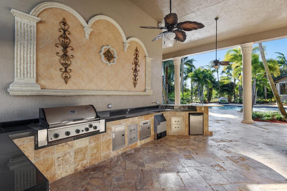 Out back, there are more areas for entertaining, with a resort-style pool and waterfall, a large deck for outdoor dining and lounging, and a full outdoor kitchen with built-in grill.