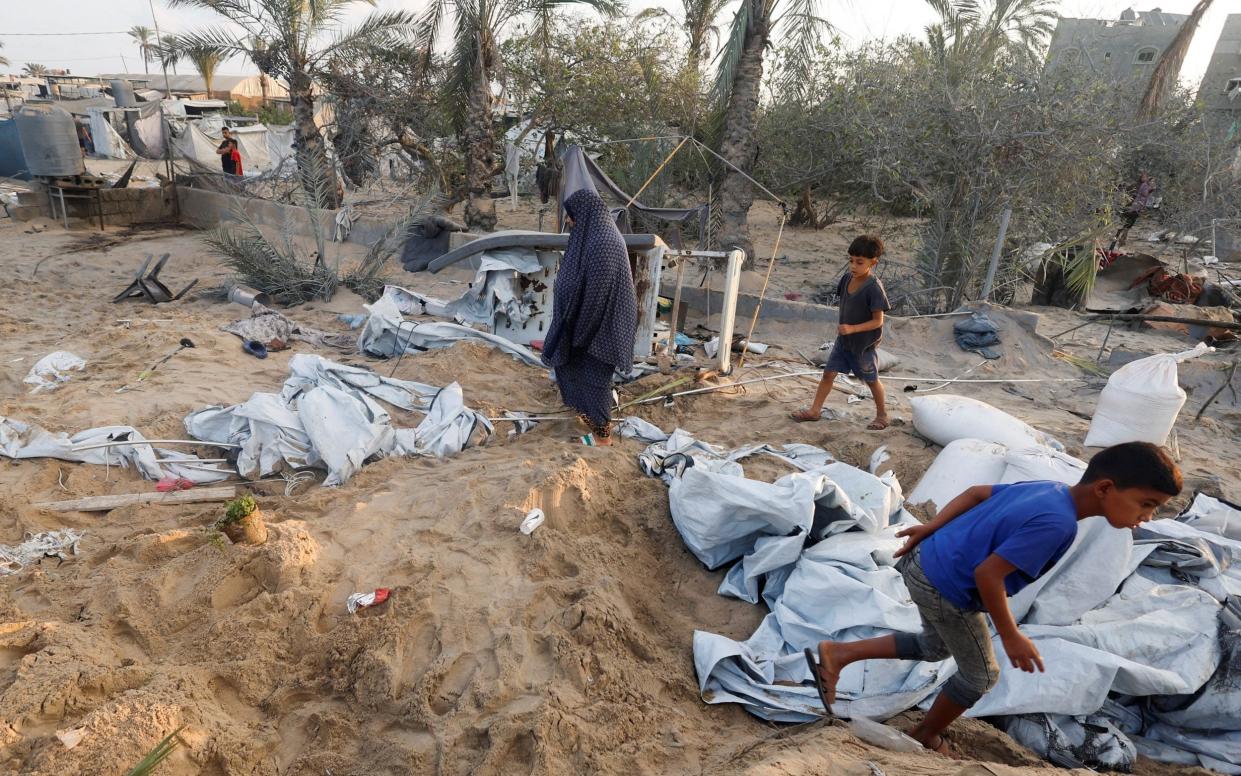 Palestinians inspect the site following Israeli strikes on a tent camp sheltering displaced people