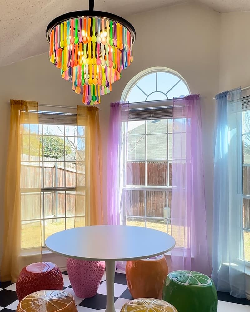 Colorful spoon themed light pendant above dining table.