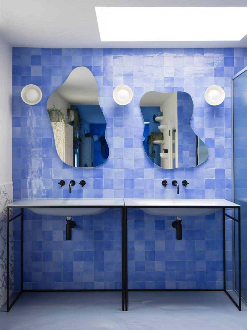 Blue tiled bathroom with puddle-shaped mirrors.