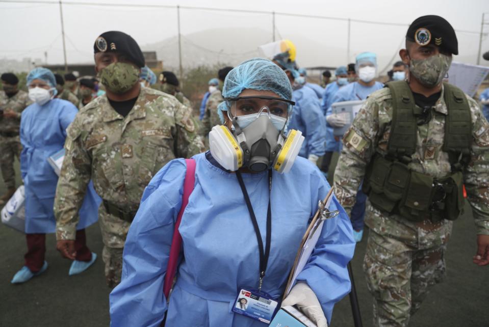 Health workers are escorted by soldiers during a house-to-house COVID-19 testing campaign in the Villa Maria del Triunfo shantytown of Lima, Peru, Tuesday, Jan. 12, 2021. As the number of infected continues to rise in Peru, soldiers are assisting with compliance and security during a massive testing effort across the capital. (AP Photo/Martin Mejia)