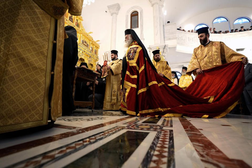 A priest hold the the mantle of the head of Cyprus' Orthodox Church Archbishop Georgios during his enthronement ceremony at Saint Barnabas Cathedral in capital Nicosia, Cyprus, Sunday, Jan. 8, 2023. Archbishop Georgios formally assumed his new duties following an enthronement ceremony evoking the splendor of centuries of Byzantine tradition before an audience of Orthodox clergy from around the world with the notable exception of the Russian church. The Cyprus Church has recognized the independence of the Orthodox Church of Ukraine. (AP Photo/Petros Karadjias)