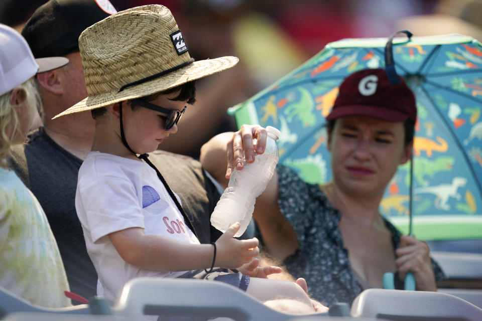A woman hands a boy a frozen water bottle during the second inning of a baseball game between the Detroit Tigers and the Los Angeles Angels in Anaheim, Calif., Wednesday, Sept. 7, 2022. (AP Photo/Ashley Landis)
