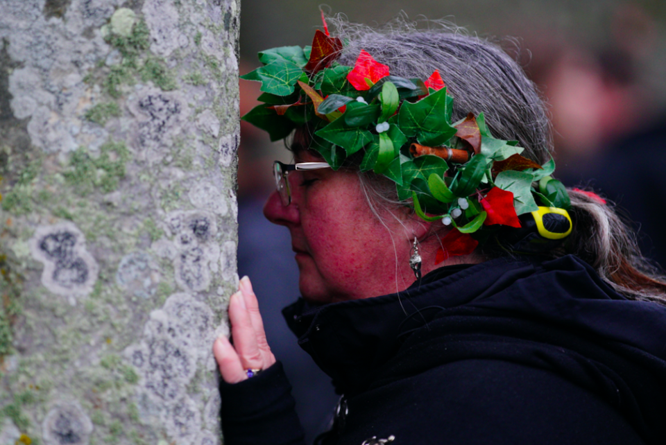 A woman embraces one of the stones at Stonehenge on the shortest day of the year. (PA)