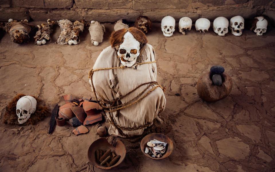 <p>Peru’s Nazca people would bury their dead fully clothed and brightly painted, placing them in a mud and brick tomb for their journey to the afterworld. In the 1920s, archeologists unearthed the mummies that now fill <a rel="nofollow noopener" href="https://strangeremains.com/2013/09/18/chauchilla-cemetery/" target="_blank" data-ylk="slk:Chauchilla Cemetary;elm:context_link;itc:0;sec:content-canvas" class="link ">Chauchilla Cemetary</a>, which were incredibly well preserved by Peru’s dry climate. While the mummies are more than 1,000 years old, many still have hair, skin, teeth, and clothing. They sit upright in their graves with their skulls staring blankly at visitors. Over the years, grave robbers plundered the necropolis, stealing earthly possessions and scattering human remains across the site. </p>