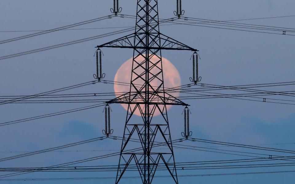 Lone splendour: a full moon setting behind pylons in Larbert near Stirling, Scotland