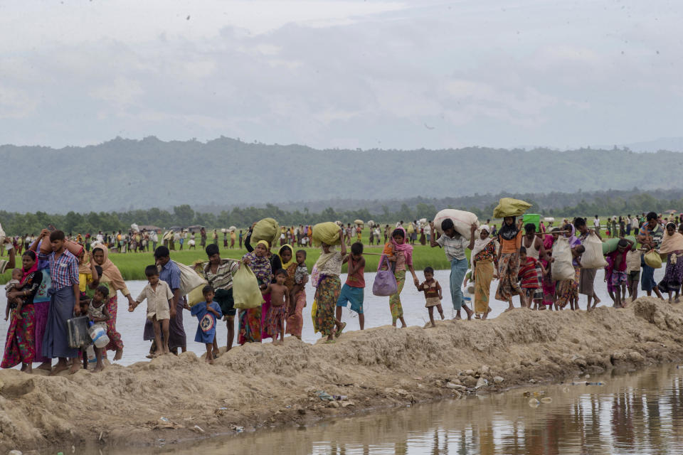 FILE - Rohingya Muslims, who spent four days in the open after crossing over from Myanmar into Bangladesh, carry their belongings after they were allowed to proceed towards a refugee camp, at Palong Khali, Bangladesh, Thursday, Oct. 19, 2017. Hundreds of thousands of Rohingya refugees on Thursday marked the fifth anniversary of their exodus from Myanmar to Bangladesh, while the United States, European Union and other Western nations pledged to continue supporting the refugees' pursuit of justice in international courts. (AP Photo/Dar Yasin, File)