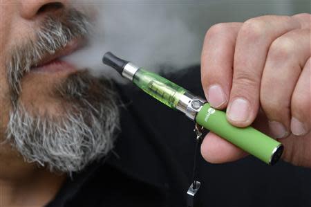 Gabor Kovacs of 'smoke no smoke' puffs on an e-cigarette that his shop sells at Camden in London in this June 9, 2013 file photo. REUTERS/Toby Melville/Files