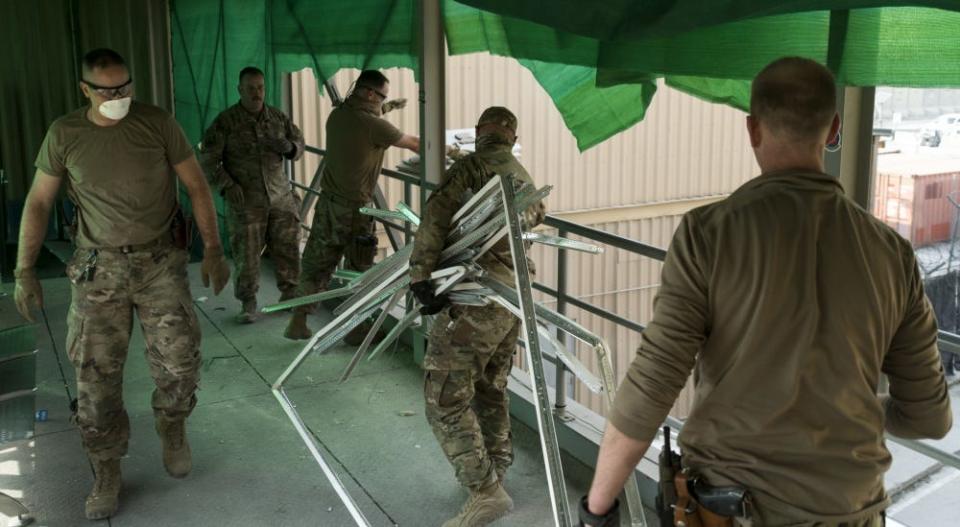 U.S. Air Force Airmen from the 405th Expeditionary Support Squadron dispose of debris into a dump truck the day after a Taliban-led attack on Bagram Airfield, Afghanistan, Dec. 12. 2019.