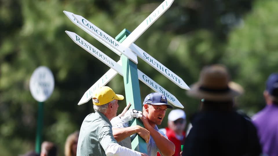 DeChambeau hauls the sign out of his shot path. - Maddie Meyer / Getty Images