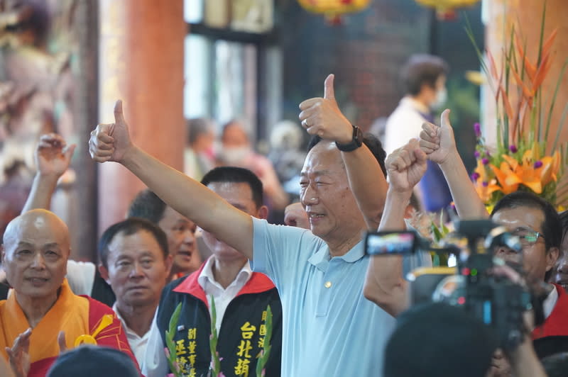 鴻海創辦人郭台銘（中）25日前往台北市士林區葫蘆寺參加中元普渡超薦大法會，雙手比讚接受媒體拍 攝。（中央社）