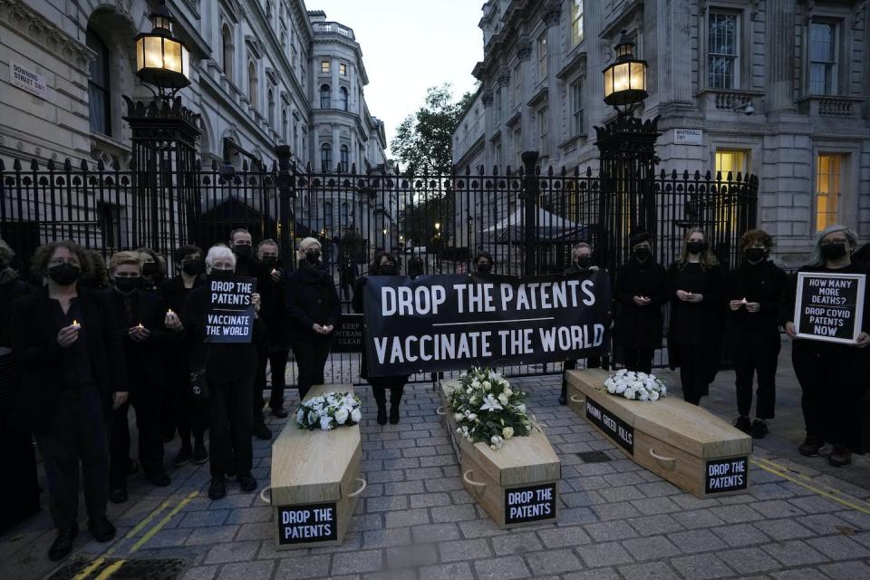 Advocacy to drop patents grew in the pandemic, seen in the work of global justice campaigners standing by fake coffins to highlight COVID-19 deaths globally, in October 2021, in London. (AP Photo/Alastair Grant)