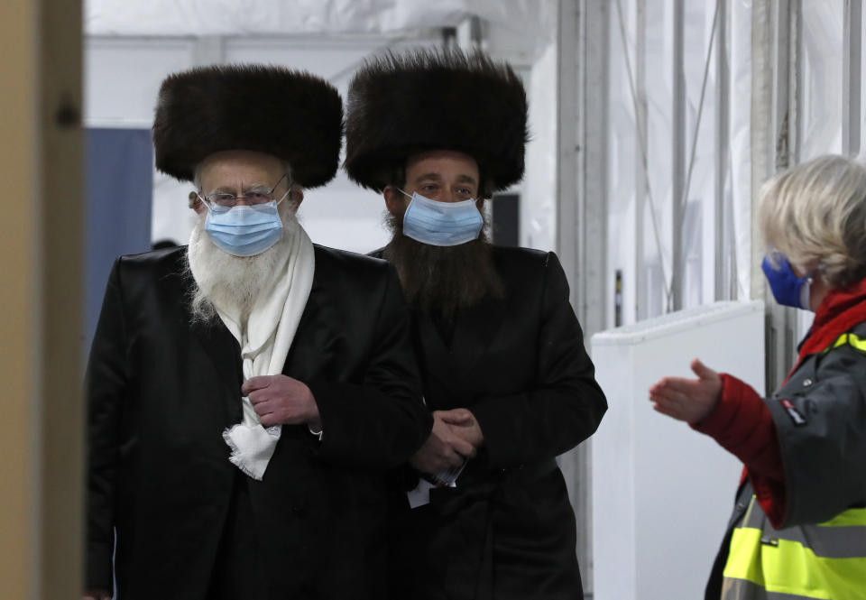 Two men from the Haredi Orthodox Jewish community arrive at an event to encourage vaccine uptake in Britain's Haredi community at the John Scott Vaccination Centre in London, Saturday, Feb. 13, 2021. The event aims to breakdown some of the misconceptions about vaccines, as well as myths and negative publicity surrounding the Haredi community which has been hard hit during the COVID-19 pandemic. (AP Photo/Frank Augstein)