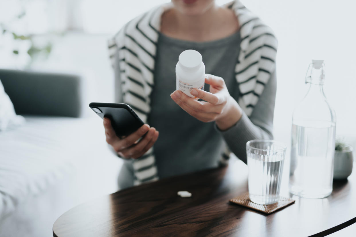 A woman examines a medication bottle.