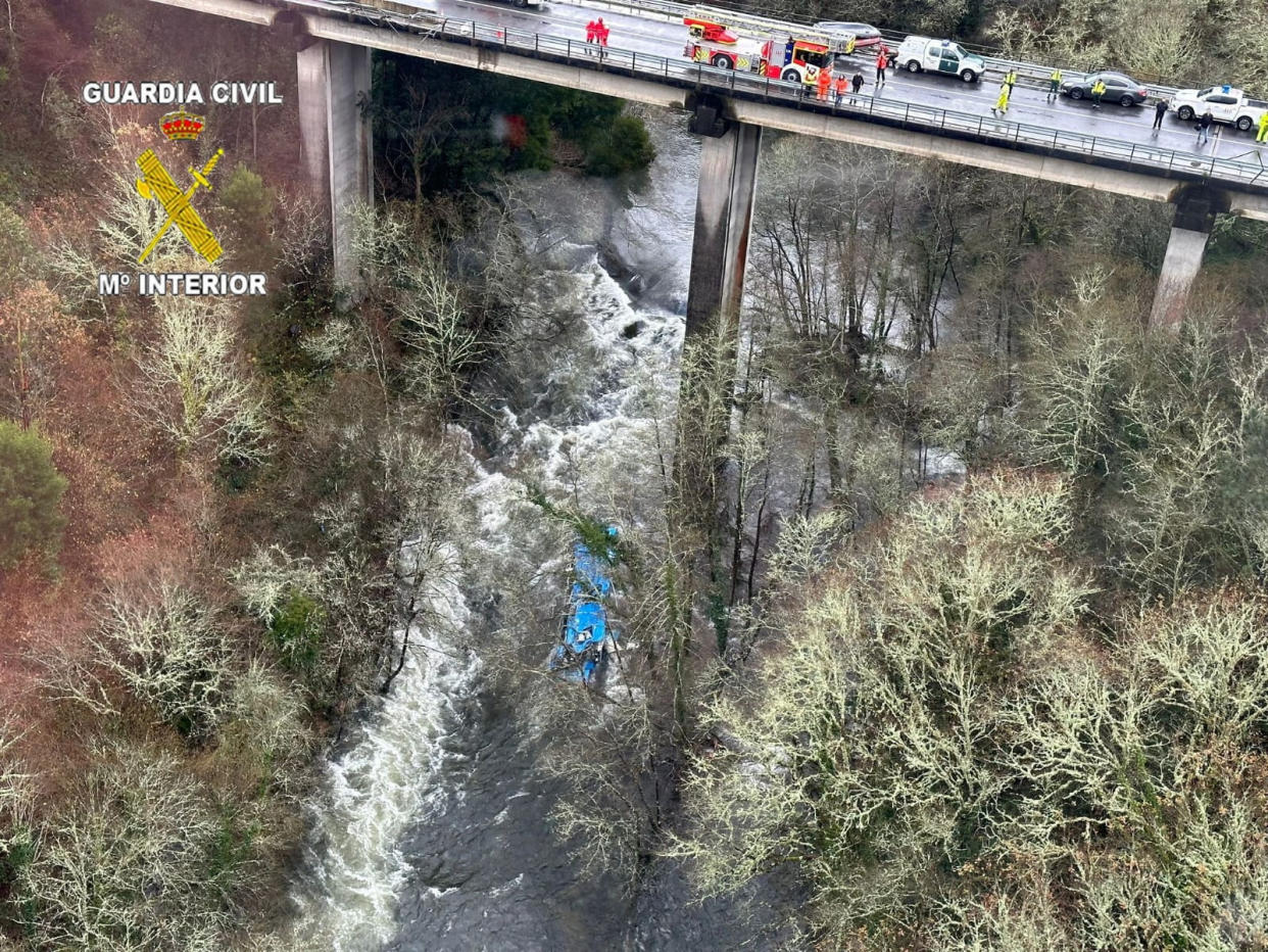 Emergency services work at the scene of an accident where a passenger bus plunged off a bridge into the river Lerez.