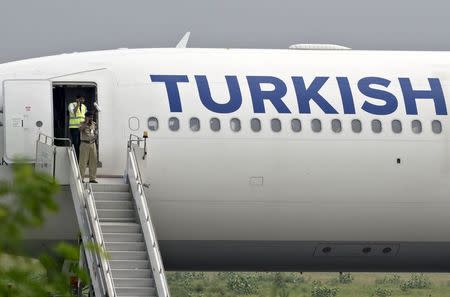 Security personnel make calls on mobile phones at a door of a Turkish Airlines passenger jet after it made an emergency landing at the Indira Gandhi International Airport in New Delhi July 7, 2015. REUTERS/Stringer