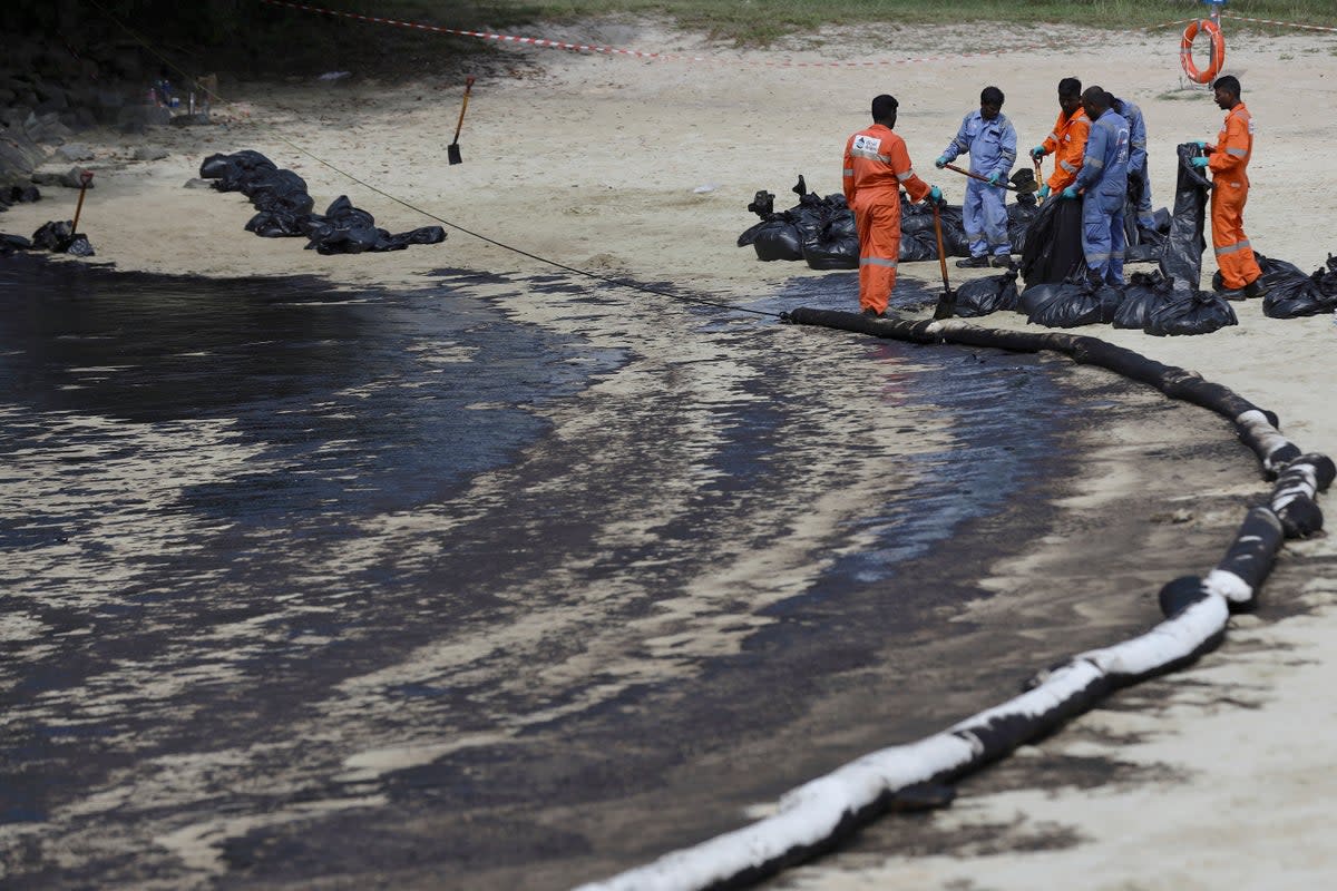 Workers clean the oil spill along Sentosa's Tanjong Beach area in Singapore (AP)