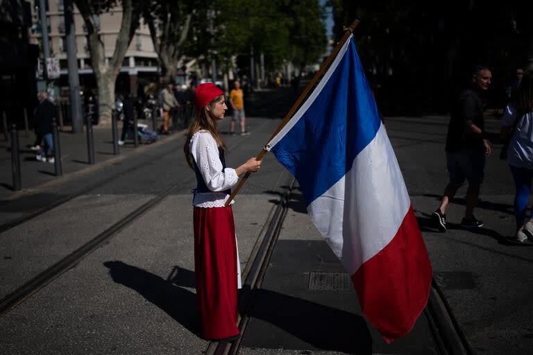 Una mujer disfrazada de Marianne, símbolo de la república francesa desde la revolución de 1789, sostiene una bandera de Francia durante los festejos del Día del Trabajo en Marsella.