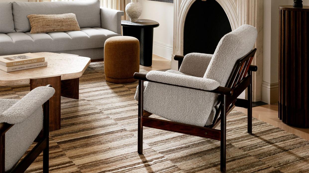 a light colored living room with a fireplace and stripey carpet in various hues of ecru and brown