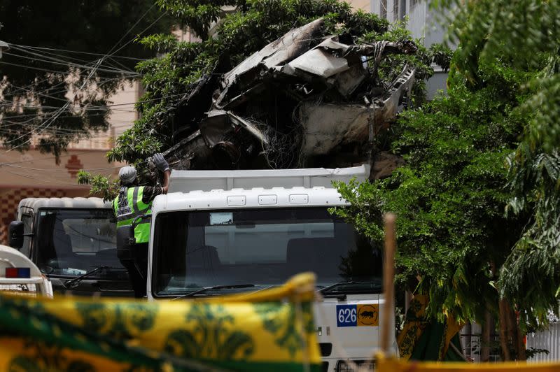 Worker gestures as the truck is loaded with the wreckage of the crashed plane, in Karachi