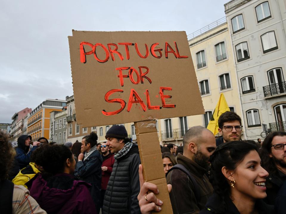 Demonstrators hoist a "Portugal For Sale" sign while gathering outside the Portuguese Parliament to demand fair housing prices and against rising cost of life on February 25, 2023, in Lisbon, Portugal.