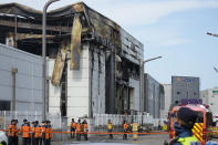 Firefighters and a police officer work outside of the site of a burnt battery manufacturing factory in Hwaseong, South Korea, Tuesday, June 25, 2024. (AP Photo/Lee Jin-man)