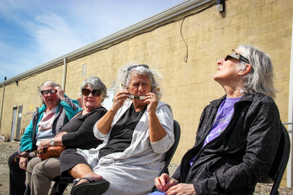 From left, Carol Mlynek, Beverly Oliveira, Toni Souliere and Ana Guillmette sit behind the North End Senior Center on Pearce Street to view the solar eclipse on April 8, 2024.